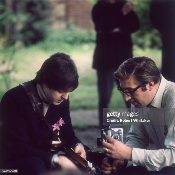 Beatles singer and songwriter Paul McCartney playing his guitar and talking to the group's road manager Mal Evans while working at Chiswick House,...