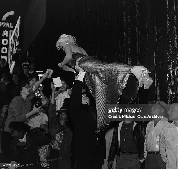 Actress Jayne Mansfield is lifted by Mickey Hargitay as she signs her autograph as they attend the premiere of "Sprit of St Louis" in Los...