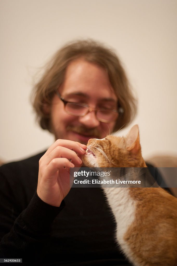 Man feeding cat treats