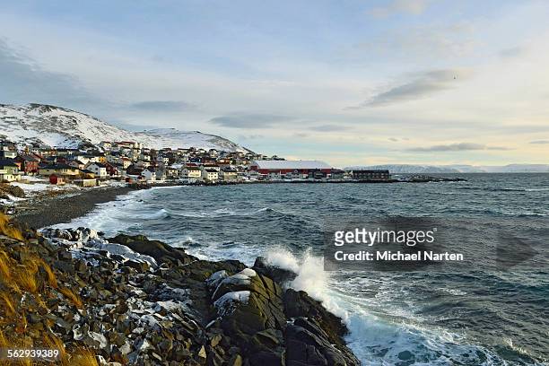 waves in a rocky bay, buildings of the honningsvag settlement at the back, mageroya island, finnmark county, norway - isola di mageroya foto e immagini stock