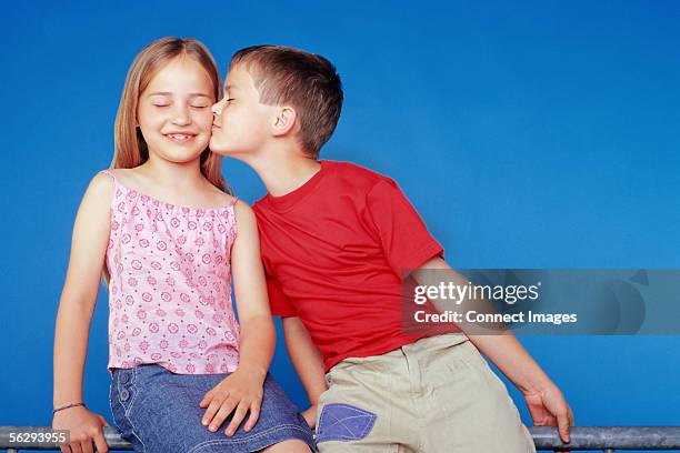 boy kissing girl on the cheek - tcs stock pictures, royalty-free photos & images