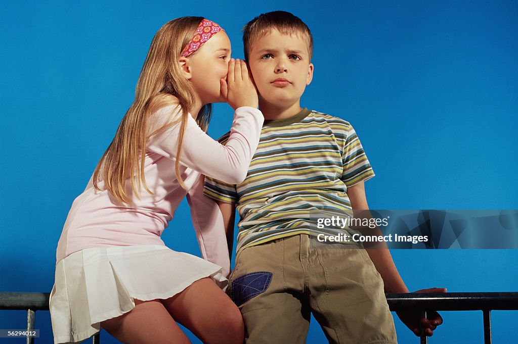 Girl whispering to boy
