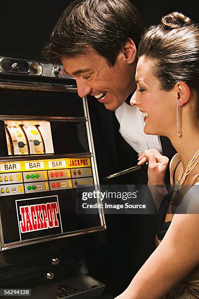 couple playing on a fruit machine - jackpot stock pictures, royalty-free photos & images