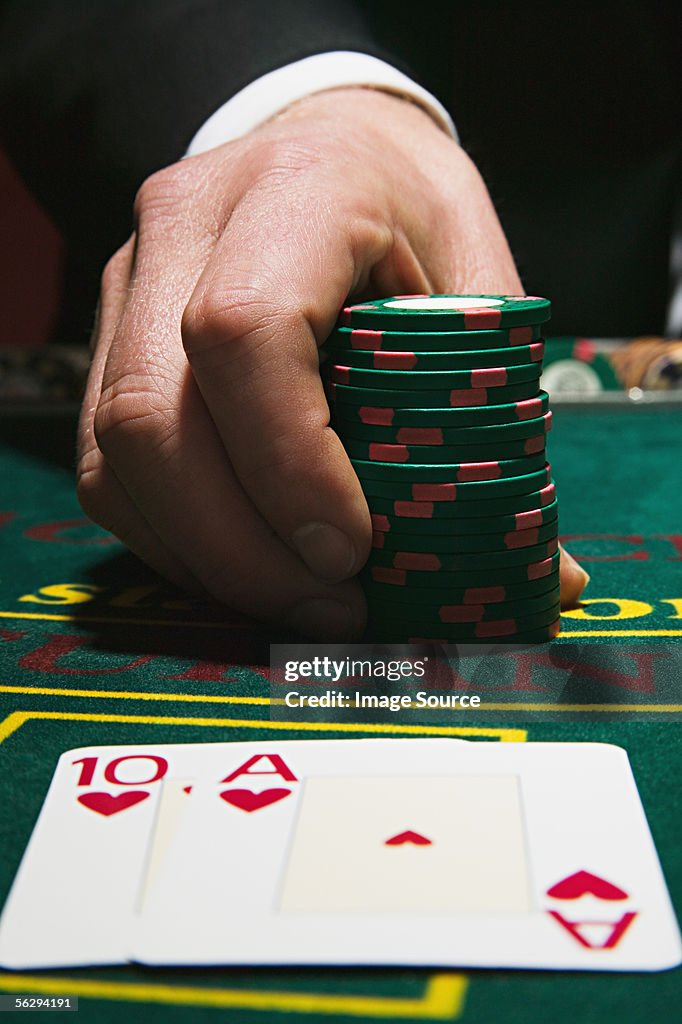 Man holding gambling chips with winning blackjack cards