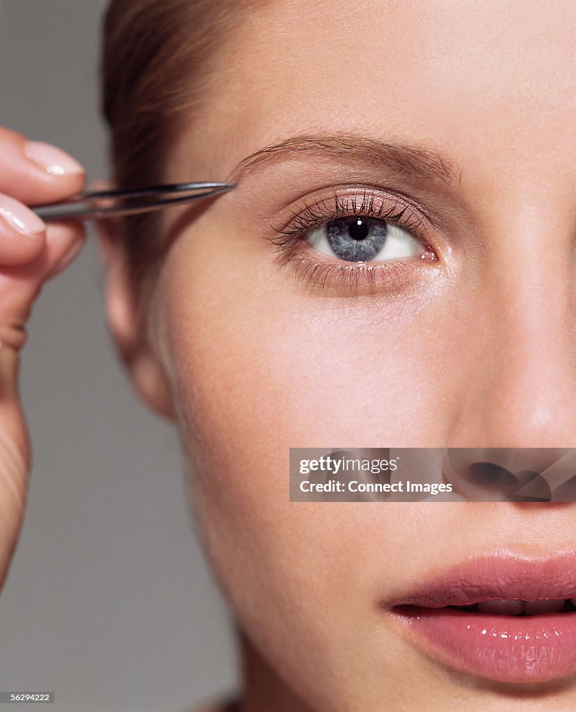 Woman plucking her eyebrow