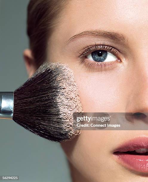 woman applying face powder - powder foto e immagini stock