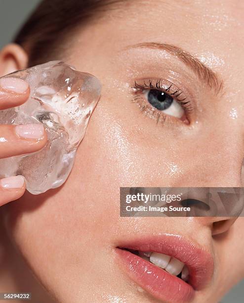 woman putting ice on her face - belleza fotografías e imágenes de stock