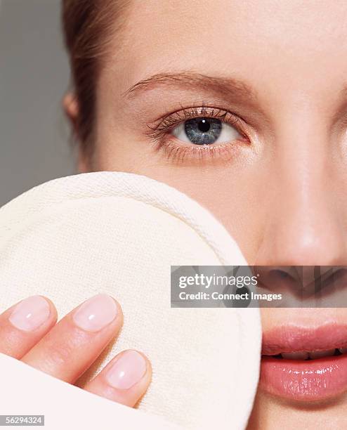 woman using loofah pad on her face - esfoliazione foto e immagini stock