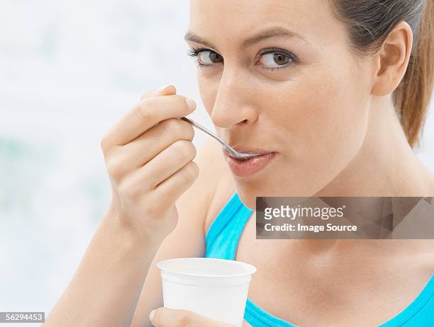 young woman eating yoghurt - yogurt cup stock pictures, royalty-free photos & images