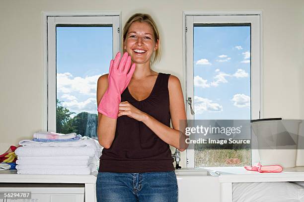 woman putting on rubber glove - spülhandschuh stock-fotos und bilder