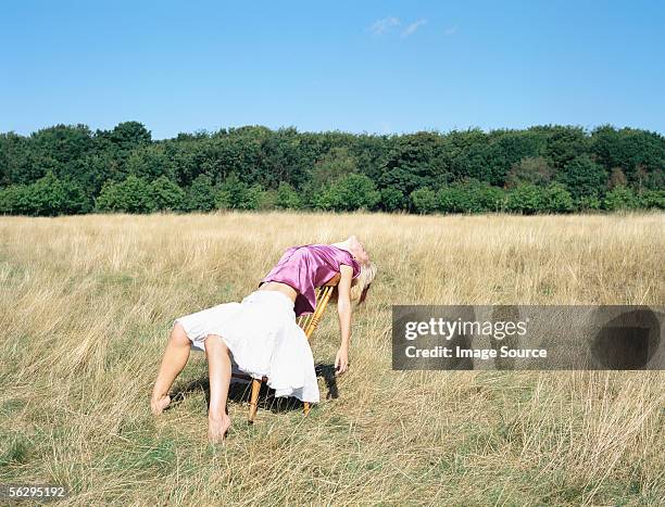 woman on a chair in a field - bending over backwards stock pictures, royalty-free photos & images