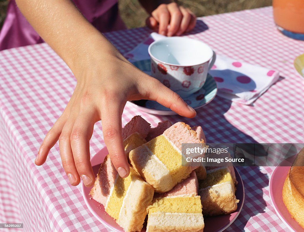 Hand reaching for a slice of cake