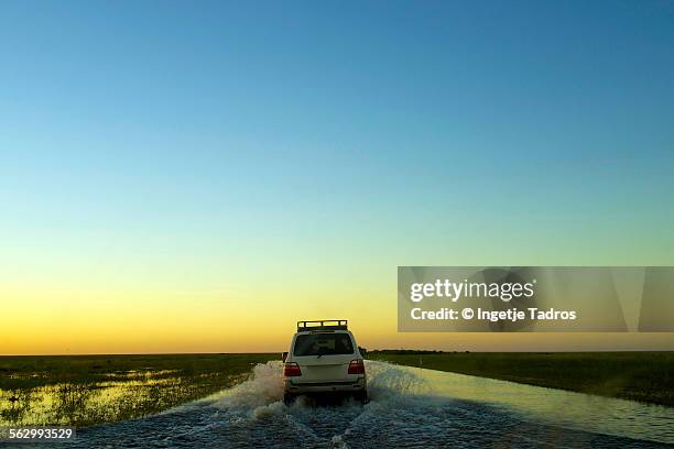 four wheel drive driving through a flooded road - roebuck bay stock pictures, royalty-free photos & images