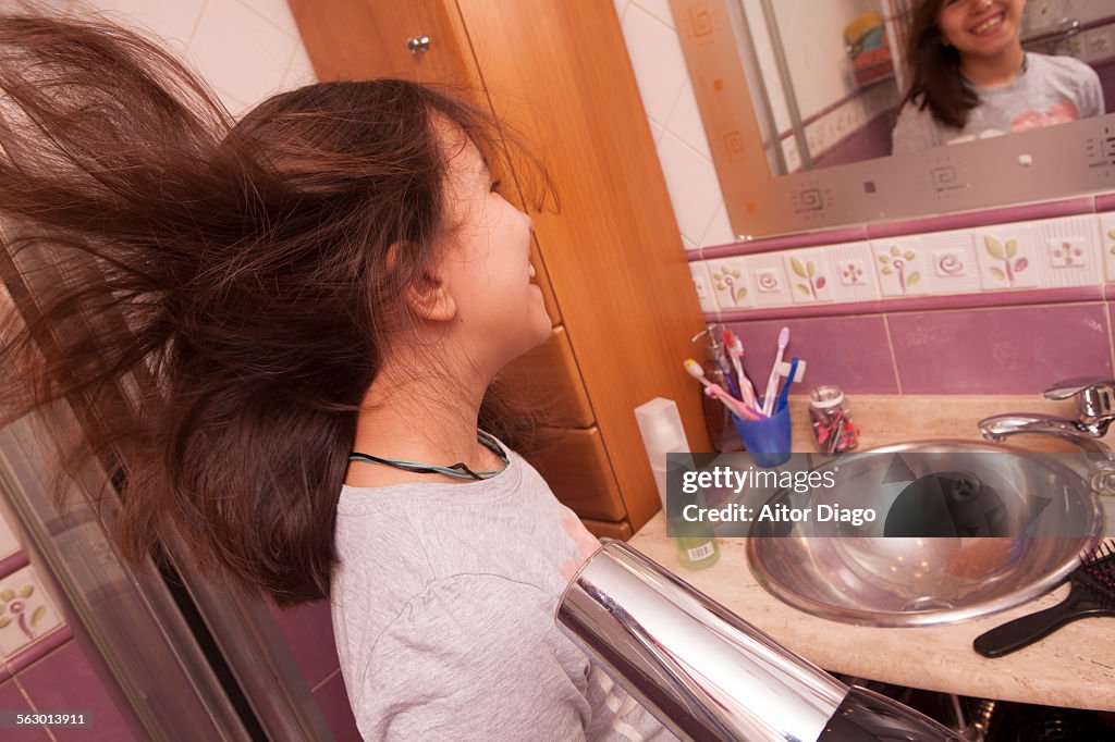 Girl blowdrying her hair in bathroom. Spain