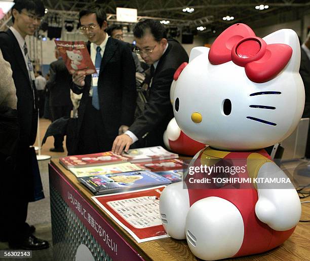 Visitors pick up leaflets about the communication robot "Hello Kitty ROBO" during the iRex 2005 international robot exhibition in Tokyo, 30 November...