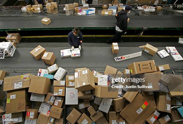 FedEx worker sorts packages being uloaded from a truck on a conveyor belt at the FedEx Oakland Airport sort facility November 30, 2005 in Oakland,...