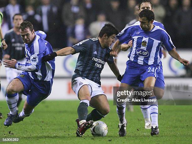 Belozoglu Emre of Newcastle United turns away from Steve McMillan and Josip Skoko of Wigan Athletic during the Carling Cup fourth round match between...