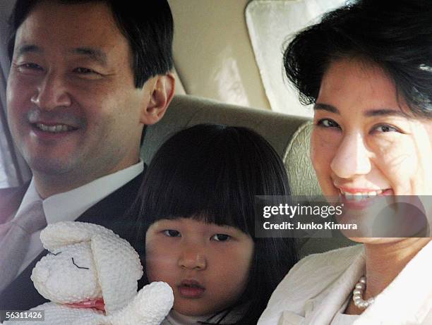 Crown Prince Naruhito, Princess Aiko and Crown Princess Masako smile as they pass by in a car upon their arrival at the Imperial Palace to greet...