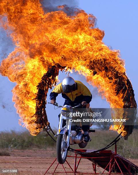 Member of the Motor Cycle team of the Indian Army "Tornado" performs a stunt as he jumps through a fire ring in Bangalore, 01 December 2005. The...