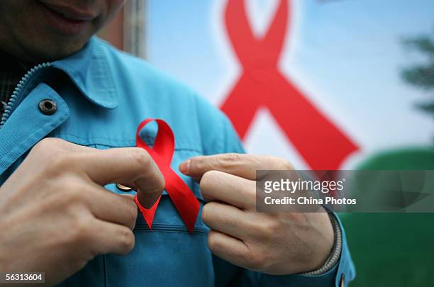 Migrant worker wears a red ribbon during an event organized by the local government to promote HIV/AIDS knowledge among migrant workers on December...