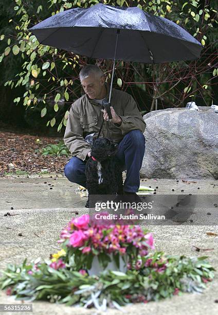 Patrick Miska crouches next to his dog as he looks at the name of a friend on the "Circle of Friends," a ring of names engraved in stone to honor...