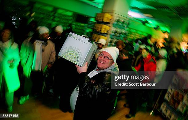 Kevin Sage holds his Xbox 360 aloft after being first in line to purchase one as people queue behind him during the official midnight launch at video...