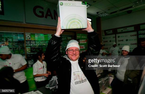 Kevin Sage holds his Xbox 360 aloft after being first in line to purchase one as people queue behind him during the official midnight launch at video...