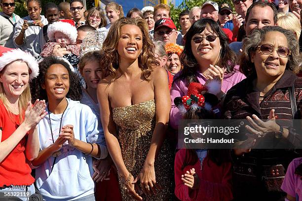 In this handout from Disney, Singer/actress Vanessa L. Williams stands with park attendees in the Magic Kingdom during a break in taping of the...