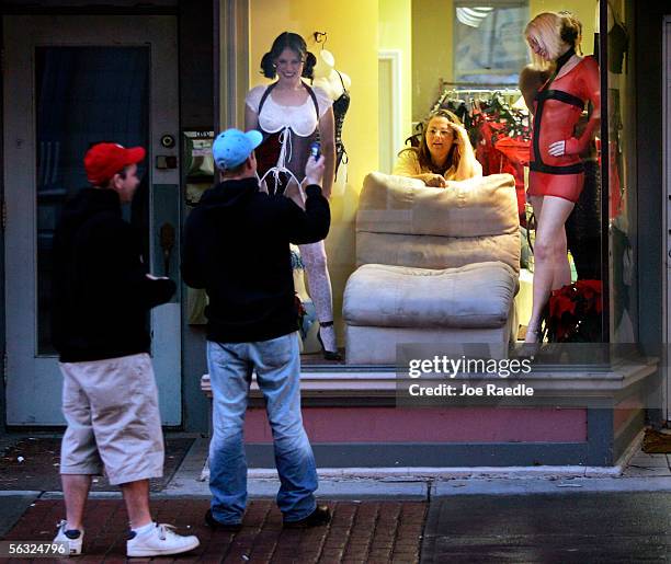 Passer by uses a cell phone camera to take a picture of Nikki Hunt , Felicia Stockford, the store owner, and Tara Manns in the store front window of...