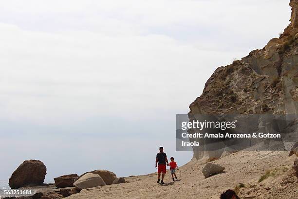 father and son walking in cala de enmedio beach - inlet stockfoto's en -beelden