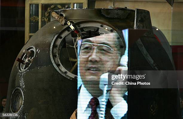 Part of video recording of Chinese President Hu Jintao phoning to astronauts, is reflected on a glass beside Shenzhou VI spacecraft re-entry capsule,...