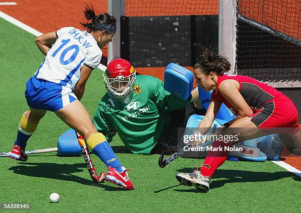 Ko Woon Oh of South Korea attacks as goal keeper Yvonne Frank and defender Tina Bachmann of Germany defend their goal during the Women's Hockey...