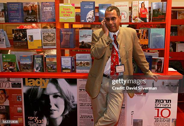 An Israeli businessman lounges against a stall, offering leading Hebrew magazines and books, to make a cell phone call during the annual Israeli...