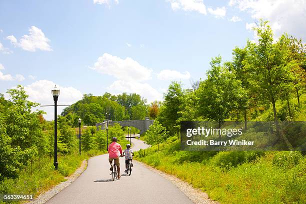 man and boy bicycling on path in atlanta park - atlanta georgia street stock pictures, royalty-free photos & images