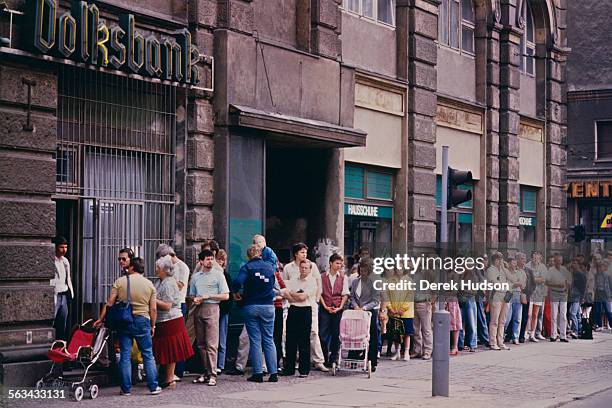 People queuing at the Volksbank to exchange their currency on the first day of the reunification of Germany, East Berlin, 1990. The Deutsche Mark is...