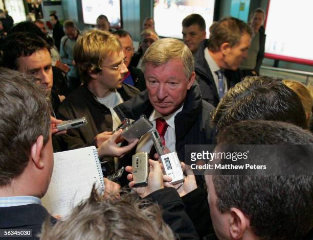 Sir Alex Ferguson of Manchester United talks to journalists after arriving at Lisbon airport ahead of the UEFA Champions League match between Benfica...
