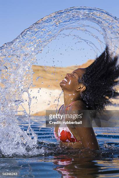 portrait of a young  woman tossing her wet hair in a lake - cheveux rejetés en arrière photos et images de collection