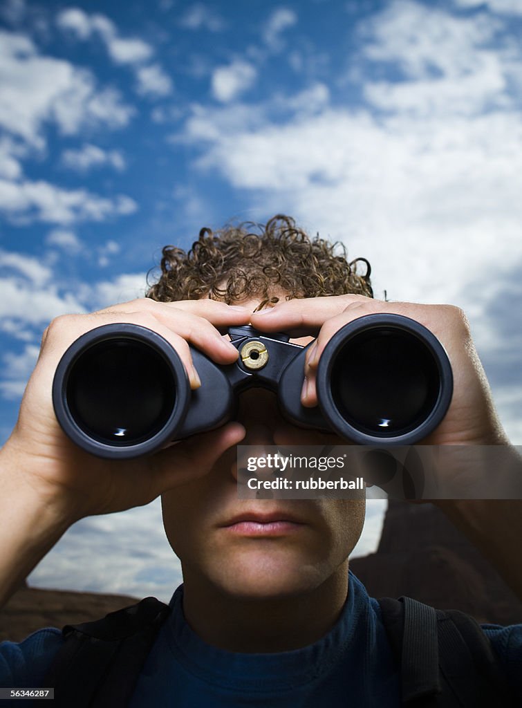 Close-up of a young man looking through binoculars