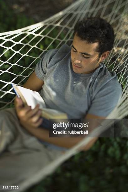 high angle view of a young man reading a book in a hammock - 2005 20 stock pictures, royalty-free photos & images