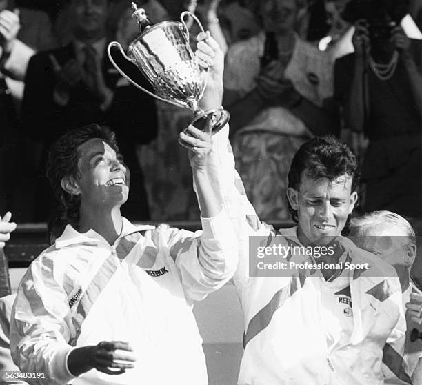 British tennis players Jeremy Bates and Jo Durie hold their trophy in the air in the Royal Box after winning the mixed doubles competition at...