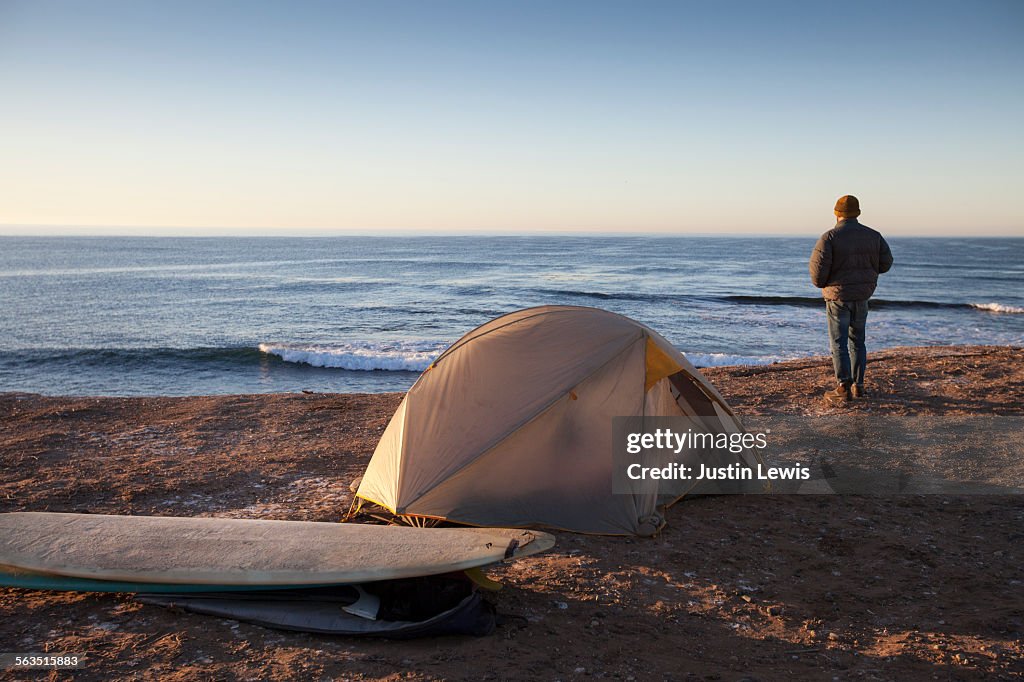 Man Alone on Beach with Tent and Surfboards