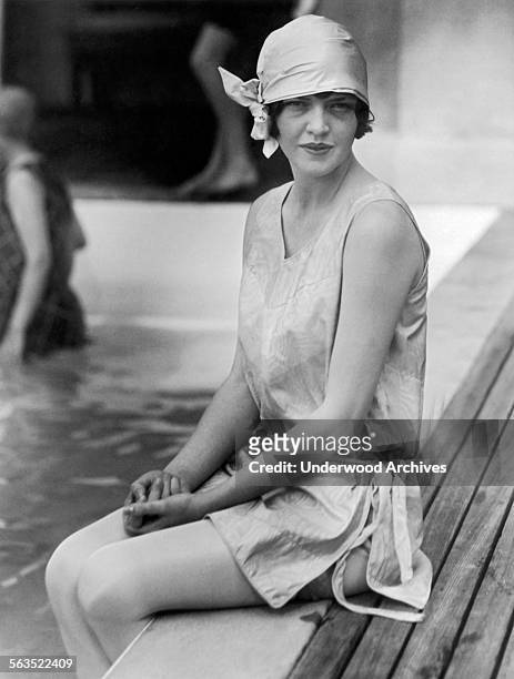An attractive young woman wearing a headscarf sitting by the side of a pool, Palm Beach, Florida, circa 1929.