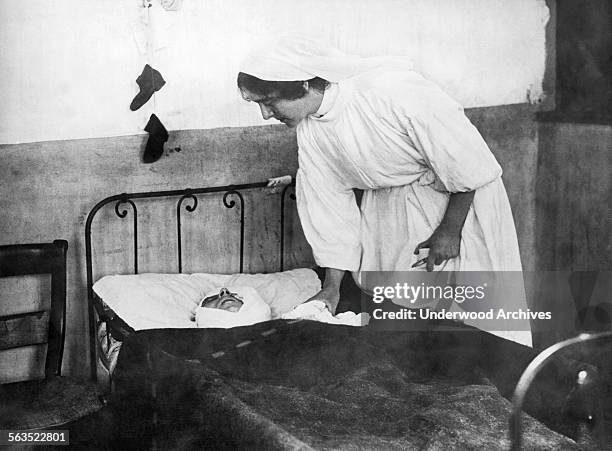 French nurse tends to a gravely wounded Belgian soldier who had penned a letter to his wife about the baby shoes he had purchased for his three year...
