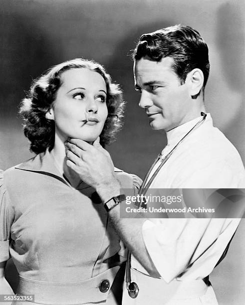 Film still of a handsome young doctor taking the temperature of and checking the glands of an attractive young woman patient, Hollywood, California,...