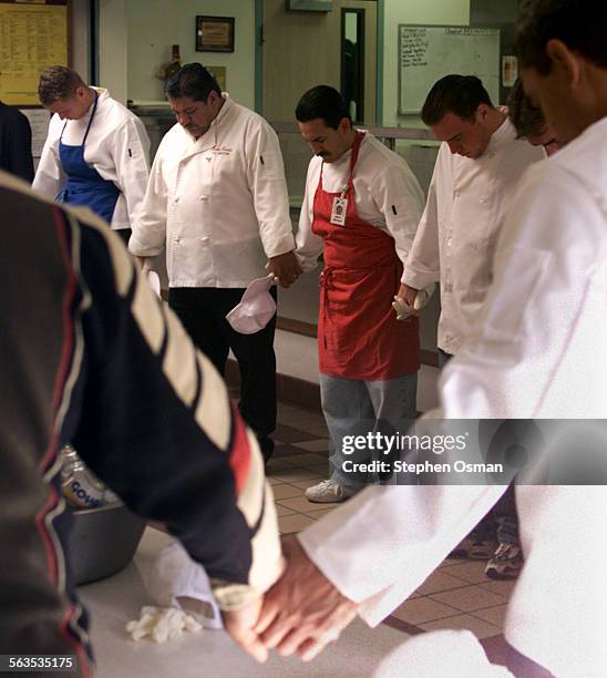 Reuben Rodriguez 39, center in red apron, prays with other participants in the Rescue Mission's culinary school before a meal is served. Rodriguez...