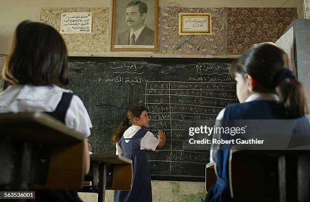 The omnipresent image of Iraqi president Saddam Hussein hangs over a fourth grade math class at Al Mutanaby elementary school in Baghdad. Experts...