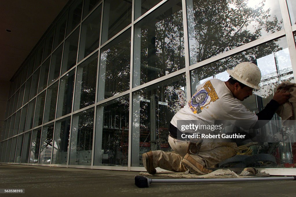 Construction worker Albert Ruiz cleans windows on a building that will become a bookstore/coffee sho