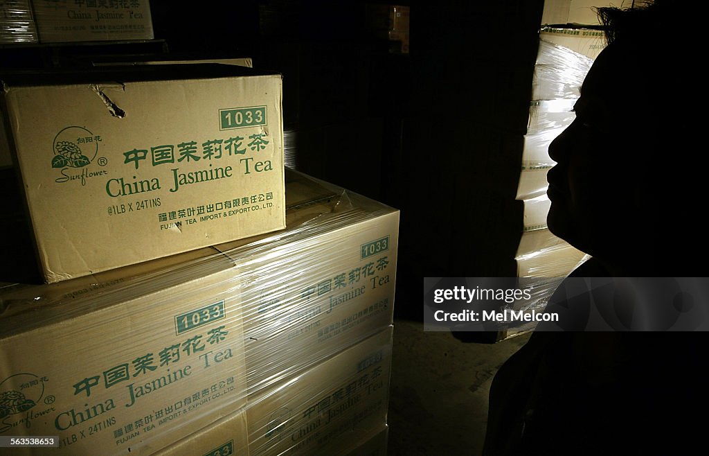 An asian food importer is silhouetted next to some of the 500 cases of China Jasmine Tea that were h