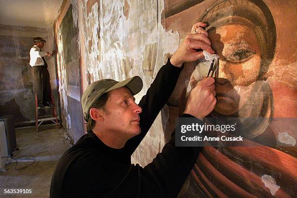 Scott Haskins and Perry Huston both working conservators remove a protective gauze layer on a mural entitled "Portrait of Mexico Today, 1932" which...