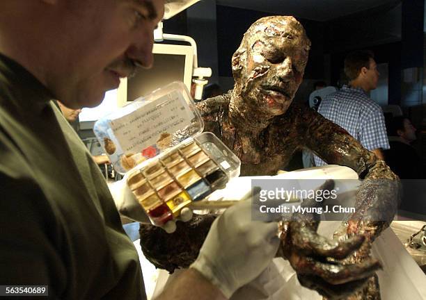 Corpses.MJC  Actor Jon Skarloff, playing a burned corpse, receives some touchup by makeup artist John Goodwin between scenes of "CSI."